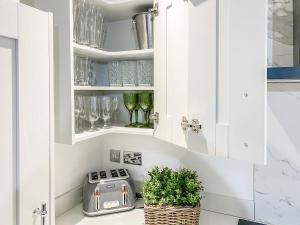 a kitchen with white cabinets and a toaster and glasses at Wharfdale Lodge in Thornton