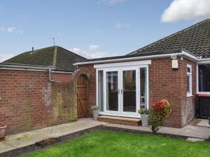 a red brick house with a sliding glass door at Wharfdale Lodge in Thornton