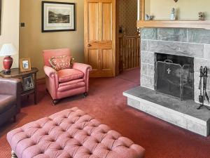 a living room with a fireplace and a pink chair at Hall Teasses Lodge - Uk52175 in Leven