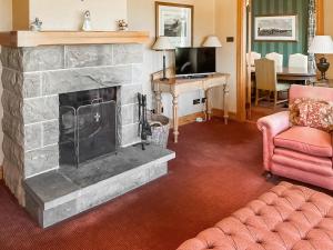a living room with a fireplace and a pink couch at Hall Teasses Lodge - Uk52175 in Leven