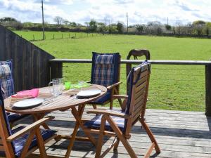 a wooden table and chairs with a horse in a field at Sunny Skies in St Austell