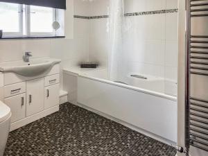 a white bathroom with a tub and a sink at Sunny Skies in St Austell