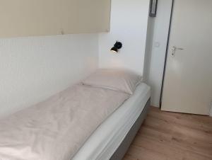 a small bedroom with a bed with a light on the wall at Haus Schildt, FeWo 3 in Duhnen