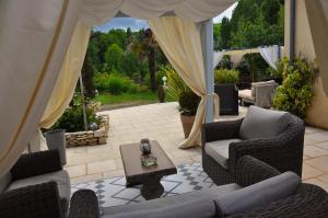 a patio with wicker chairs and a table and curtains at Ô Reflet du Lac in Groléjac