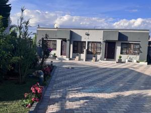 a white building with a brick driveway in front of it at MAITA Apartments - Silverest, Lusaka in Chongwe