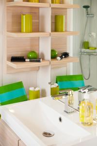 a bathroom with a sink and two green chairs at Camping Paradis Le Pearl in Argelès-sur-Mer