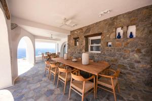a dining room with a stone wall and a wooden table and chairs at Eagles Nest Mykonos Suites & Apartments - Shared Pool & Jacuzzis in Mikonos