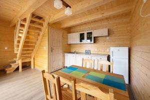 a wooden kitchen with a table and a refrigerator at Domki Prima Baltic in Sarbinowo