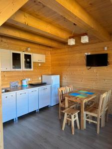 a kitchen and dining room with a table and chairs at Domki Prima Baltic in Sarbinowo +20 photos