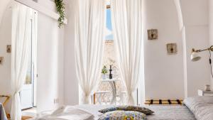 a white bedroom with a bed and a window at 21mq Suite Jacuzzi in Ostuni +14 photos