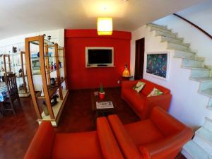 a living room with an orange couch and a staircase at Pousada Aldeia dos Ventos in São Pedro da Aldeia
