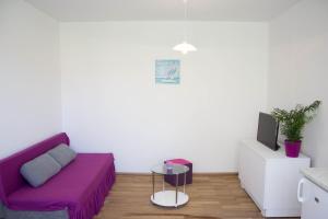 a living room with a purple couch and a tv at Apartman Renata in Biograd na Moru