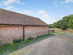 an old brick building with a dirt road next to it at Coblye Barn in Battle