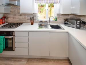 a kitchen with white cabinets and a sink at Bluebird Lodge 2 - Uk50932 in High Nibthwaite