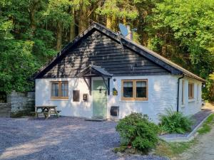 a small white house with a bench in front of it at The Glen in Devils Bridge