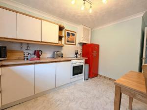 a kitchen with white cabinets and a red refrigerator at No 1 The Martins in Southwold +24 photos