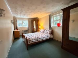 a small bedroom with a bed and two windows at No 1 The Martins in Southwold