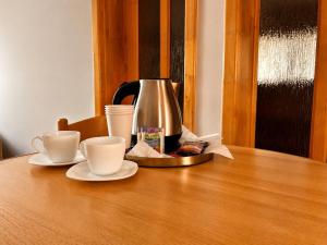 a coffee pot and two cups on a wooden table at Spring Apartments in Gheorgheni