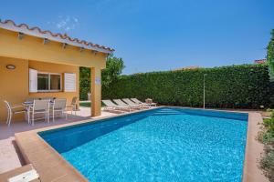 a swimming pool with chairs and a house at Villa Aries by 3VILLAS in Cala en Forcat