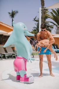a man holding a baby standing next to a dolphin statue at Suites & Villas by Dunas in Maspalomas +78 photos