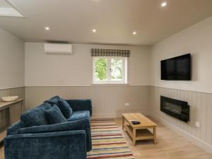 a living room with a blue couch and a tv at Foxglove in Bicester