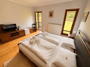 a large white bed in a room with a television at Spring Apartments in Gheorgheni