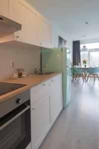 a kitchen with white cabinets and a blue refrigerator at Amsterdam Beach Apartment 80 in Zandvoort