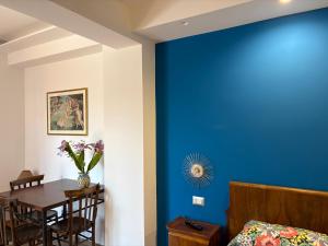 Ein Zimmer mit einer blauen Wand und einem Tisch mit einer Blumenvase in der Unterkunft B&B Domus Candida in Calatabiano