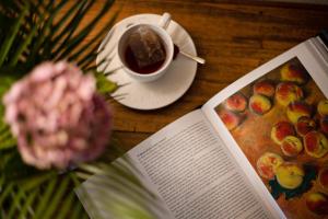 a table with a book and a cup of coffee and a flower at VM Boutique in Castiglione di Ravenna