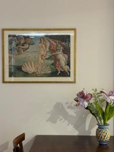 Ein Gemälde hängt an einer Wand neben einer Vase mit Blumen. in der Unterkunft B&B Domus Candida in Calatabiano