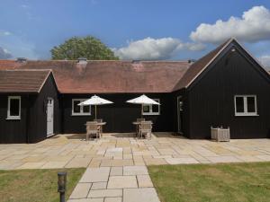 a black building with tables and umbrellas on a patio at Poppy Patch in Bicester