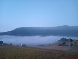 a foggy field with a mountain in the background at Hotel Himalayan Inn, khona in Pātan