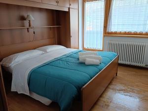 a bedroom with a large bed with blue sheets and white pillows at Villa Clelia in Auronzo di Cadore