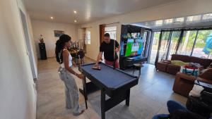 a man and a woman playing a game on a pool table at Entre Mer et Volcan ,piscine chauffée au tampon in Bel Air