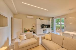 a living room with two couches and a kitchen at Appartamenti Villa Andrea in Garda