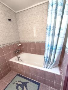 a bath tub with a blue shower curtain in a bathroom at Sea View Villa w Garden 50m to Sarımsaklı Beach in Ayvalık +60 photos