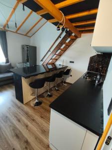 a kitchen with a black counter top and bar stools at Zeigių apartamentai in Normantai +20 photos