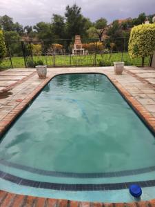a large pool with blue water in a yard at Riverside Cottages in Graaff-Reinet