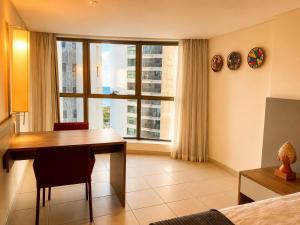 a room with a desk and a table and a window at Luxo na Beira Mar - Beach Class Executive 105 in Recife +21 photos