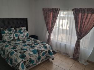 a bedroom with a bed and a window with curtains at Charles Guest House in Germiston