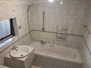 a bathroom with a bath tub and a sink at Charles Guest House in Germiston