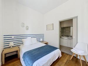 a white bedroom with a bed and a chair at Le Cours Langlet B in Reims