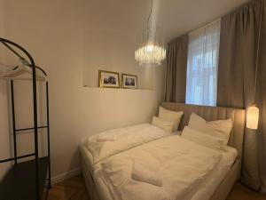 a bedroom with a bed with white sheets and a chandelier at Monte-Rosa in Karlovy Vary