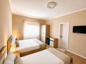 a hotel room with two beds and a flat screen tv at Villa Tabaku in Berat