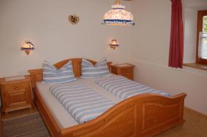 a bed with blue and white striped pillows on it at Vilahof in San Vigilio Di Marebbe +5 photos