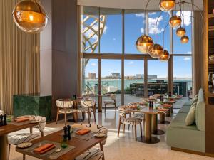a restaurant with tables and chairs and a large window at SO Ras Al Khaimah Hotel & Resort-Ultra All Inclusive in Ras al Khaimah