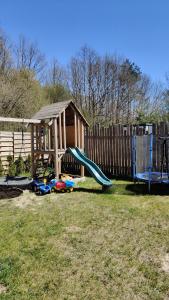 a playground with a slide and a wooden fence at Domek Las nad jeziorem in Bożepole Królewskie