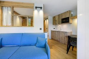 a living room with a blue couch and a kitchen at Appartement Le Panorama Des Pistes in Les Menuires