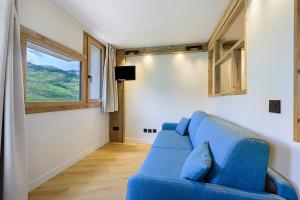 a blue couch in a living room with a window at Appartement Le Panorama Des Pistes in Les Menuires