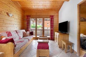 a living room with a couch and a flat screen tv at Appartement Airelles B25 in Levassaix